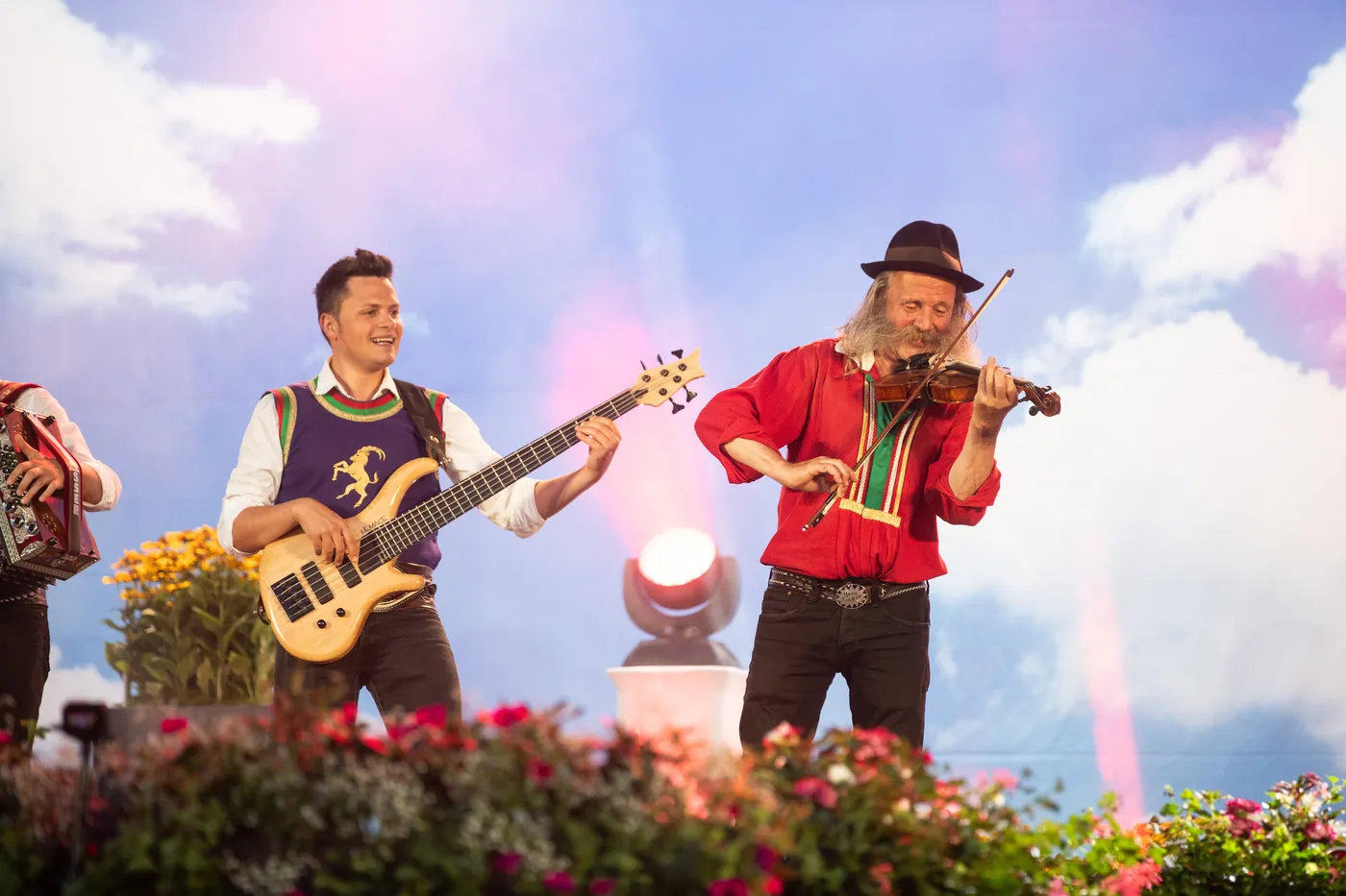 Musiker in Tracht mit Bassgitarre und Geige auf einer Bühne