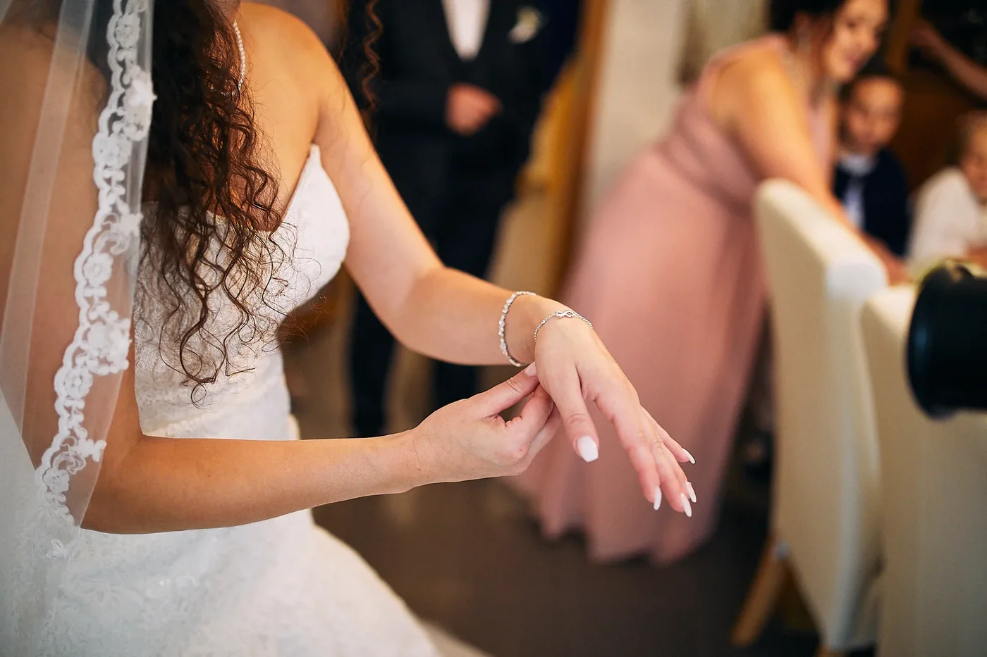 Getting Ready: Braut im Spitzenkleid legt sich ein Armband an