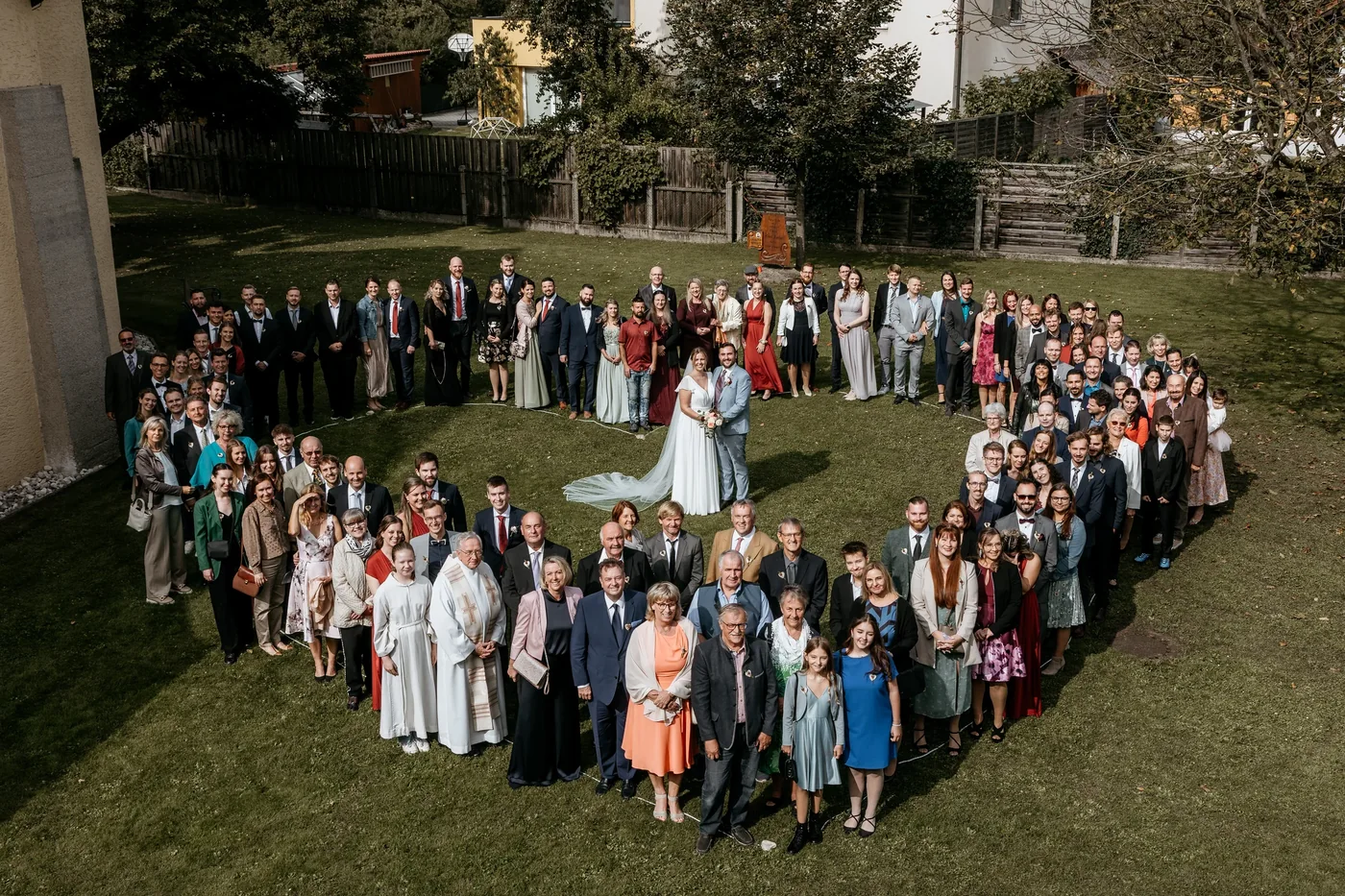 Gruppenfoto von oben: Hochzeitsgäste stehen in Herzform um das Brautpaar