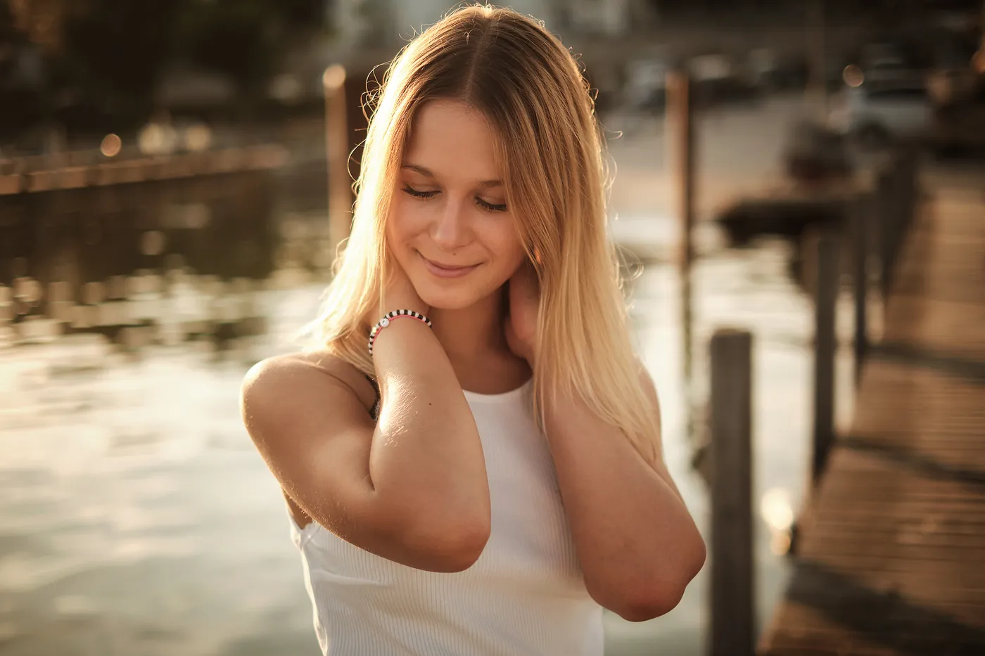 Lächelnde blonde Frau im Gegenlicht am Wasser